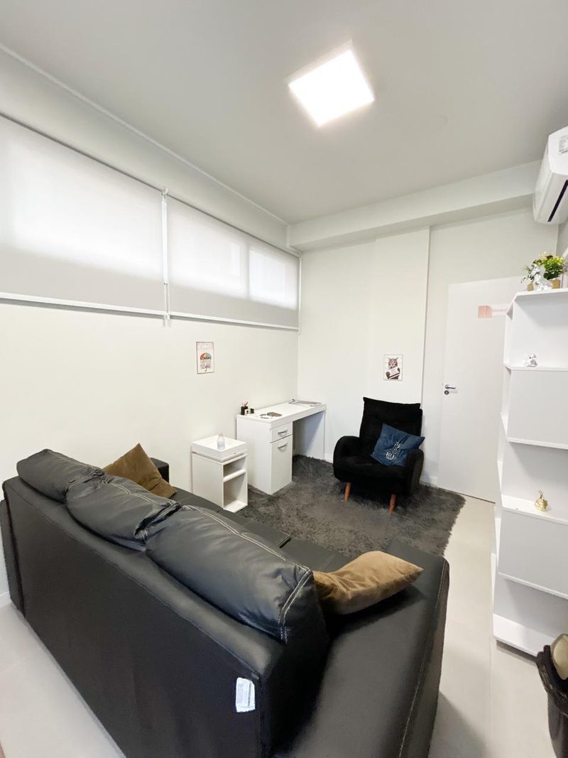 Sala de atendimento com sofá, poltrona e escrivaninha